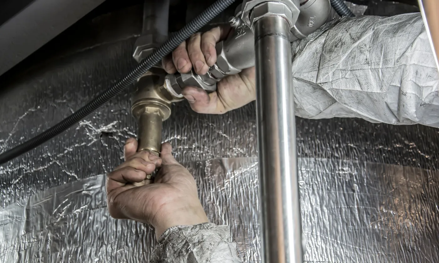 Plumber repairing steel supply pipe indoors